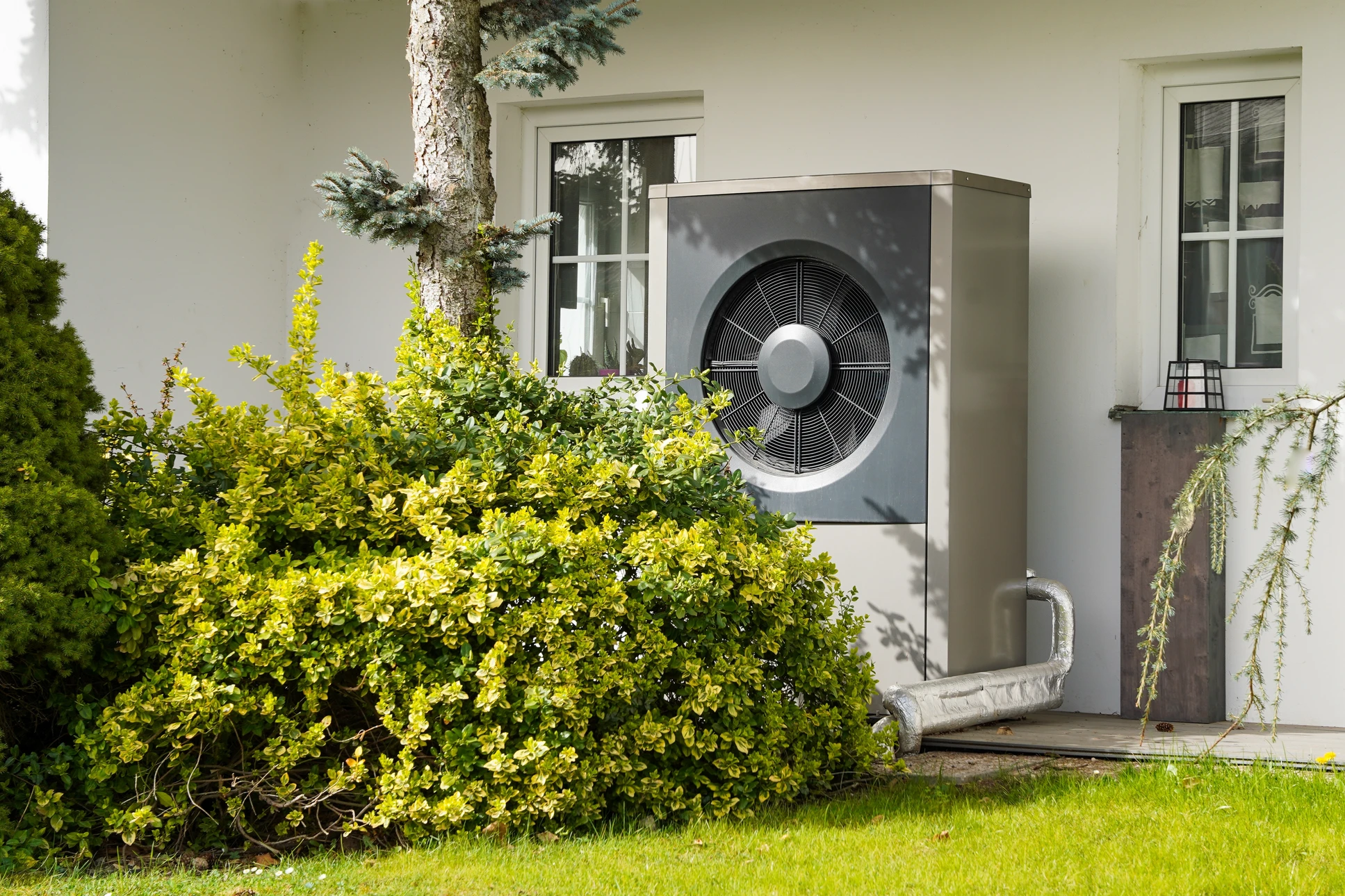 Scène extérieure résidentielle avec pompe à chaleur air-eau installée sur terrasse moderne